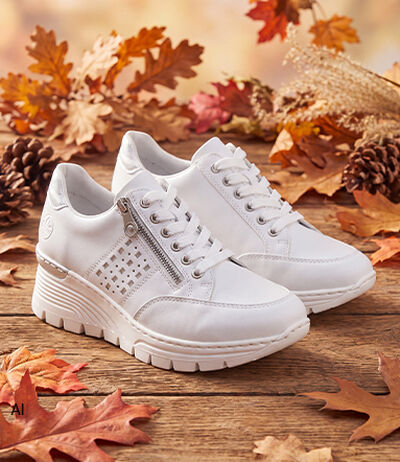 Wei&szlig;e Sneaker mit Keilsohle auf Herbstlaub