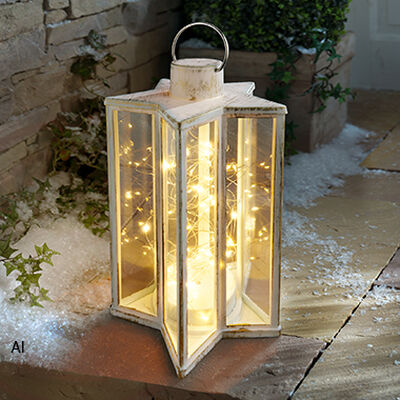 Wei&szlig;e Gartenlaterne mit warmwei&szlig;er LED-Lichterkette auf einer winterlich dekorierten Terrasse