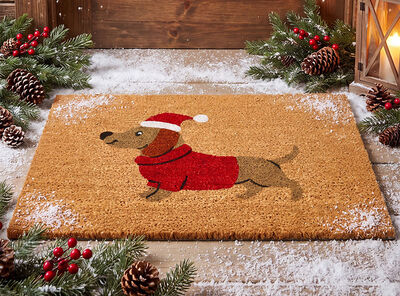 Braune Fu&szlig;matte mit weihnachtlichem Dackelmotiv in rotem Pullover und Nikolausm&uuml;tze vor einer Haust&uuml;r