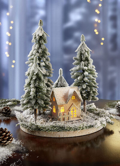 Beleuchtetes Winterhäuschen mit Tannen 